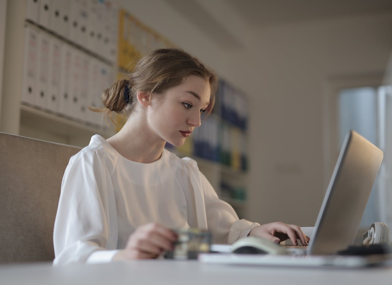Home Focused woman in white working on a laptop in a modern office setting.