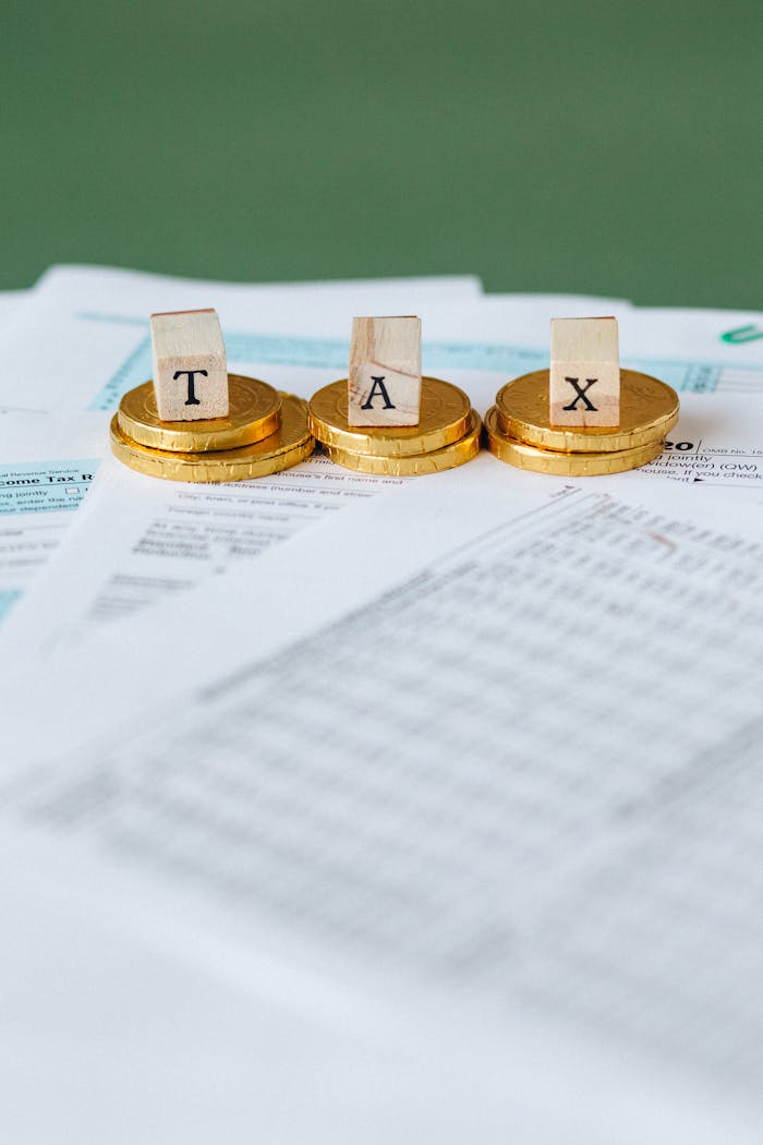 Home Staged image of gold coins with tax letter tiles on documents.